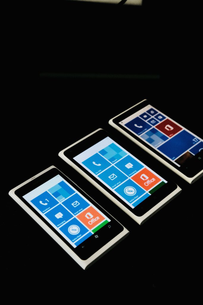 Three smartphones on a black background showcasing blue home screens with apps.